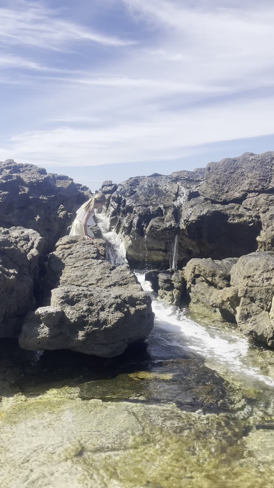 Clear water cascading over dark rocks into a pool